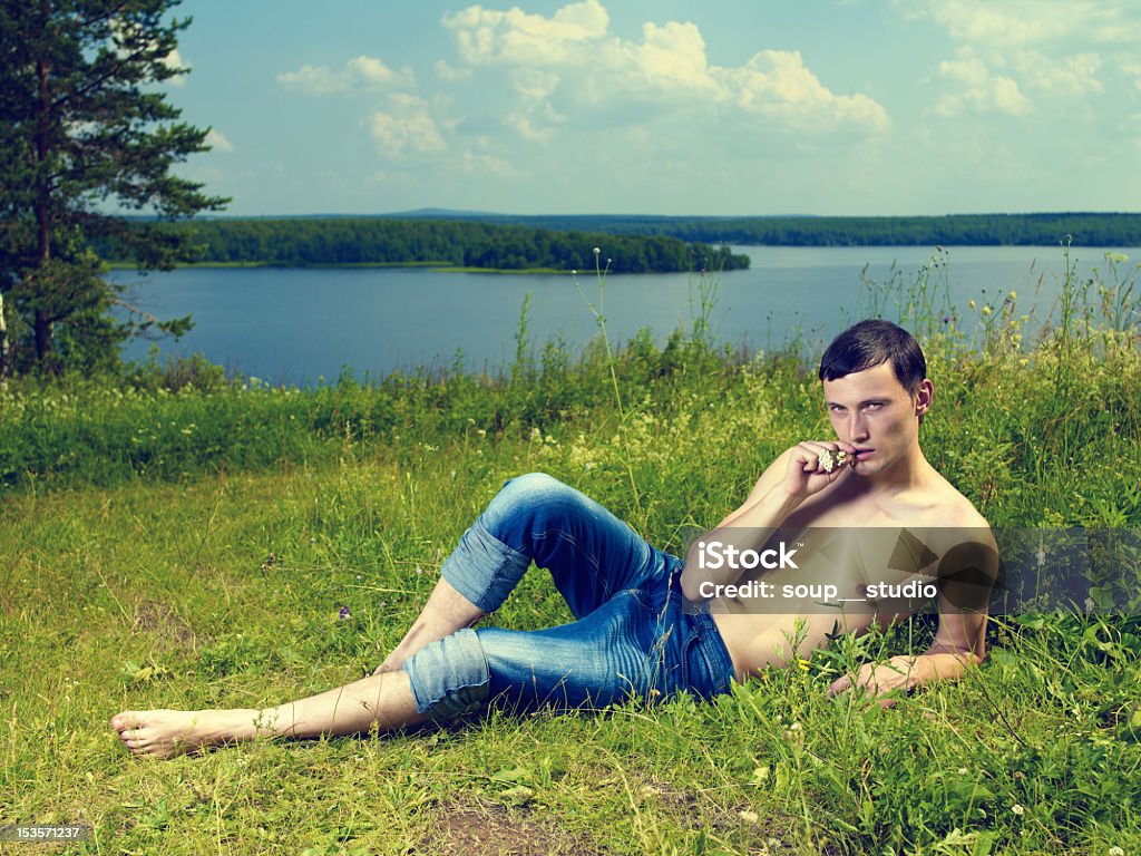 Jeune homme allongé sur prairie - Photo de Fleuve et rivière libre de droits