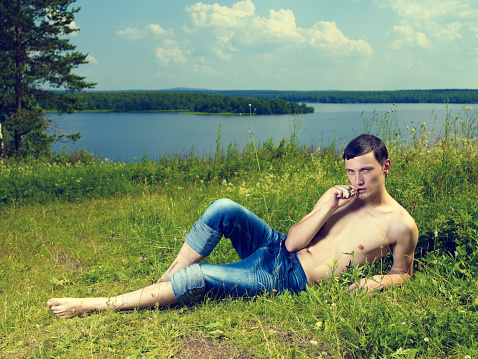 A handsome young man, lying on a sunny summer meadow