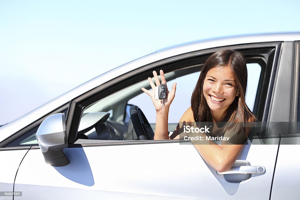 Car driver woman Asian car driver xwoman smiling showing new car keys and car. Mixed-race Asian and Caucasian girl. Car Stock Photo