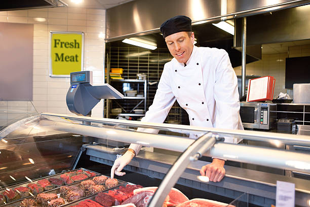 新鮮な肉カウンターにブッチャー - supermarket sales clerk grocer apron ストックフォトと画像