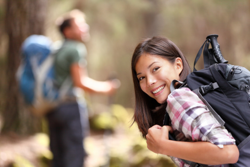 Hiking. xwoman hiker smiling in forest with male hiker in the background. Mixed-race Asian Caucasian female model happy. From Aguamansa, Tenerife, Spain