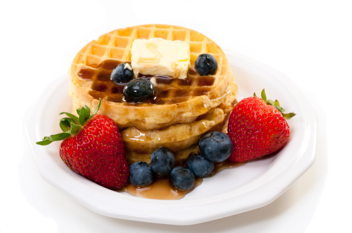 Waffles, strawberries, blueberries, and butter.   Isolated on white background.