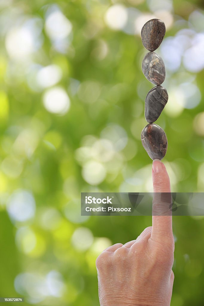 Mano di equilibrio pietre su un dito con sfondo sfocato verde - Foto stock royalty-free di Abilità