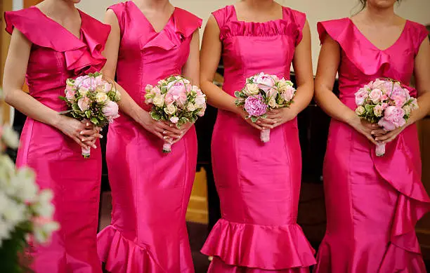 Photo of Row of bridesmaids with bouquets at wedding ceremony