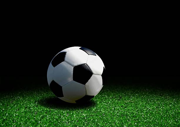 istock Soccer ball on grass over black background 153574377