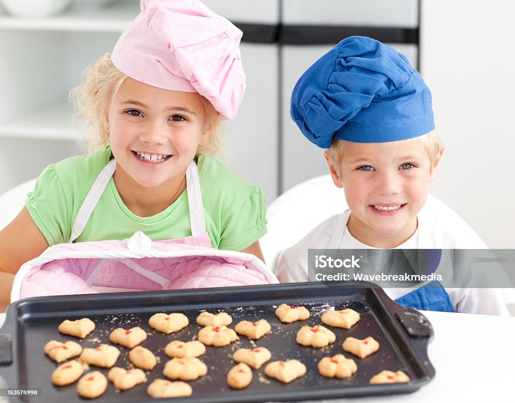 Happy little brother and sister with their biscuits Happy little brother and sister with their biscuits ready to eat standing in the kitchen Cake Stock Photo