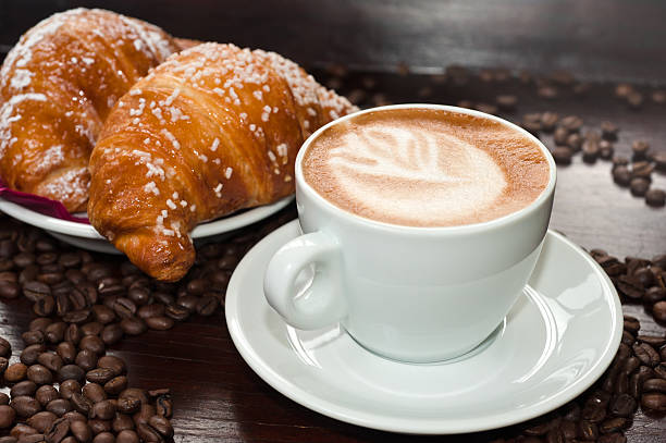 istock Cappuccino and croissants on a table with coffee beans 153575490