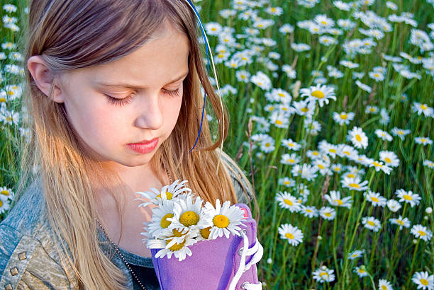 Young girl holding a purple sneaker with daisy bouquet.