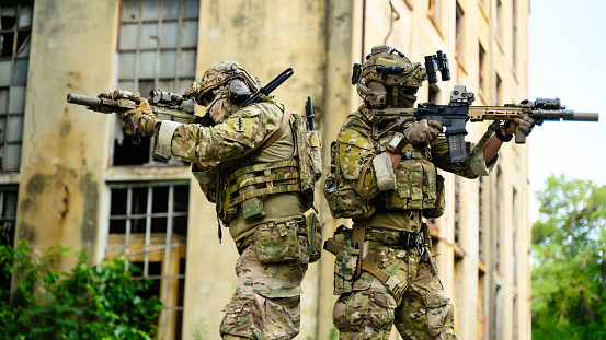 Expert team of soldiers attacking enemy during military operation, Army soldiers in protective combat uniform, Soldiers with rifle on world war field. High quality photo