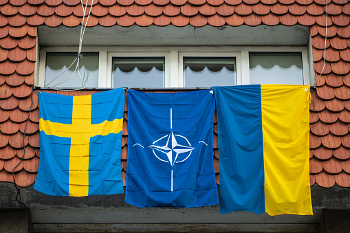 Vilnius, Lithuania - July 11 2023: Flags of NATO, Sweden and Ukraine waving on the window during Nato summit 2023 in the centre of Vilnius, Europe