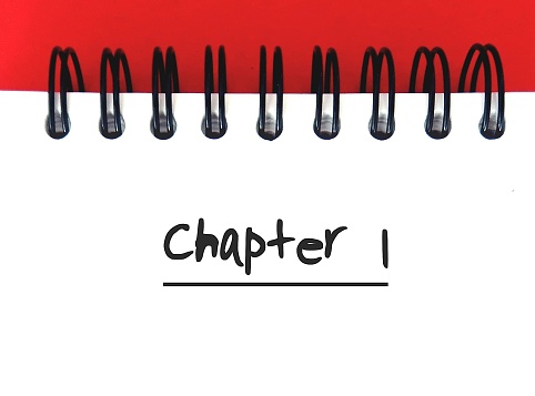 Notebook on red background with text written CHAPTER 1, concept of start writing books - novel fiction non-fiction, first time writer or author
