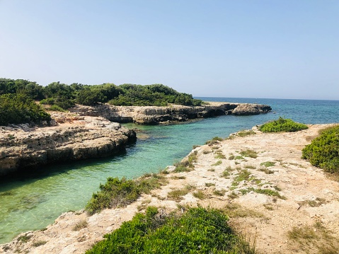 Scenic Rock formations on sandy beach. Views of the Mediterranean Sea from the coast of the Costa Blanca, Torrevieja, Alicante, Spain. Sea landscape with line of horizon. Coastline. Nature background.