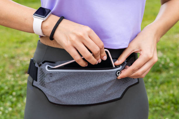 donna corridore di fitness che si prepara a correre con smartwatch e smartphone in un marsupio. - purple belt foto e immagini stock