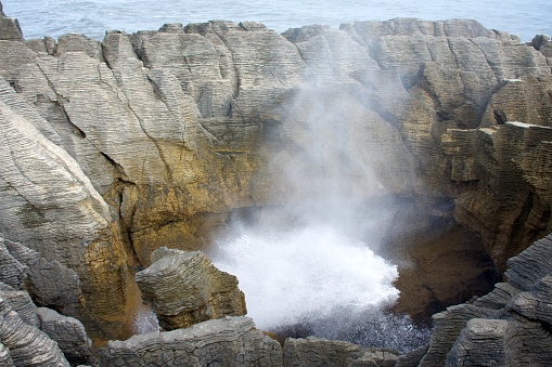 Sea water surges up into a surge pool at high tide. Taken at the Punakaiki Rocks viewpoint between Westport and Greymouth on the West Coast of New Zealand. The Punakaiki viewpoint is a limestone landscape of pancake-shaped rock formations, blowholes and surge pools.