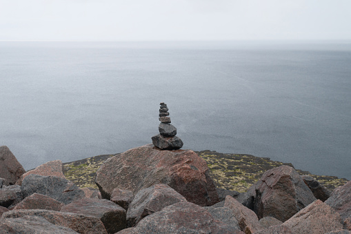 pyramid of stones near the ocean. the sea is in fog