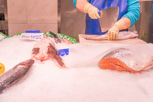 detail of a woman's hands cutting fish at the market