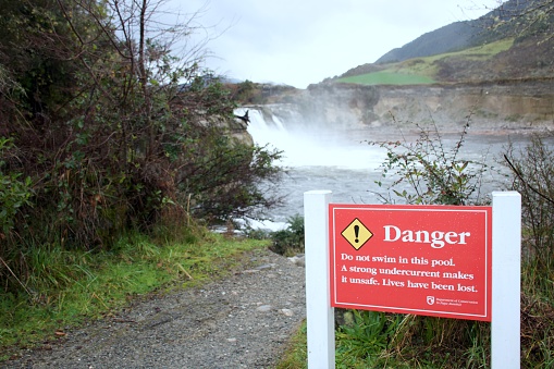 Maruia, New Zealand - July 03 2023. A danger sign warns 'Do not swim in this pool. A strong undercurrent makes it unsafe. Lives have been lost.' This DOC sign was taken at Maruia Falls landmark in New Zealand's South Island. The Maruia Falls are the result of a devastating earthquake in the Murchison township in 1929.