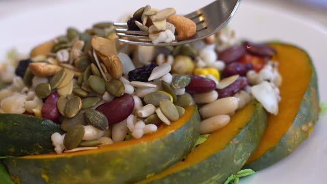 Healthy vegan whole grain salad, good meal for vegetarians. streamed pumpkin, almond, whole grain and vegetables on dish.