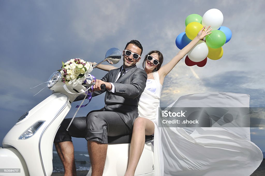 Just married couple ride a white scooter wedding scene of bride and groom just married couple on the beach ride white scooter and have fun Couple - Relationship Stock Photo