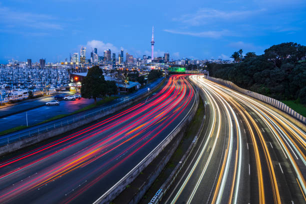 Futuristic city traffic trails with cityscape in background at night.