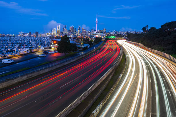 Futuristic city traffic trails with cityscape in background at night.