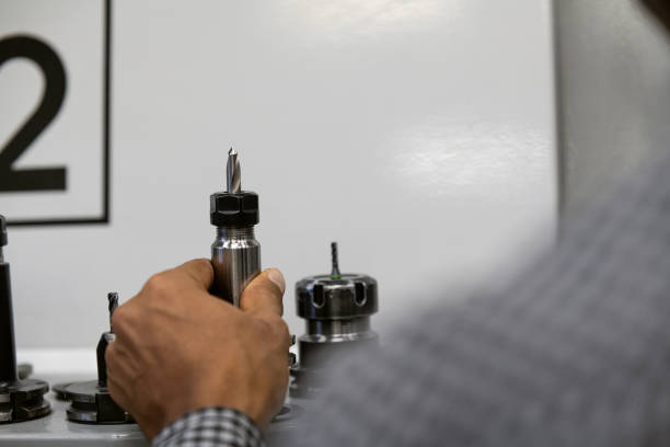 The hand of a black worker holds a drill head with a drill bit