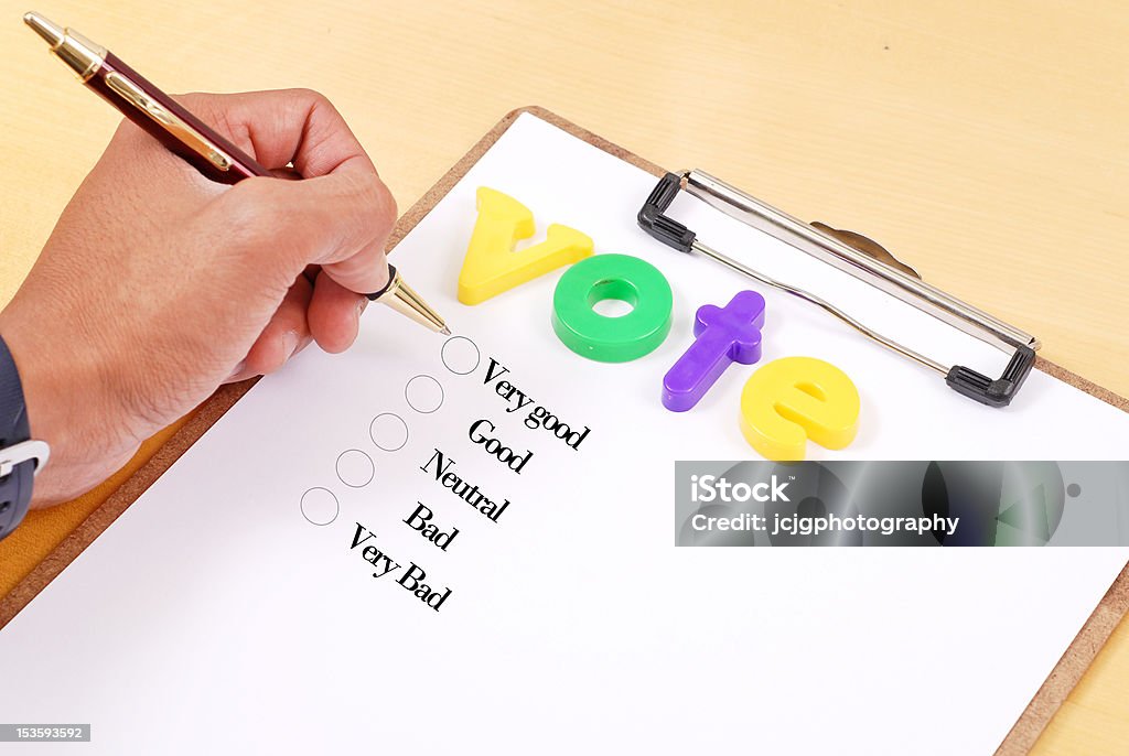 Your Opinion Matters Hand with pen making a choice on paper with voting choices Choice Stock Photo