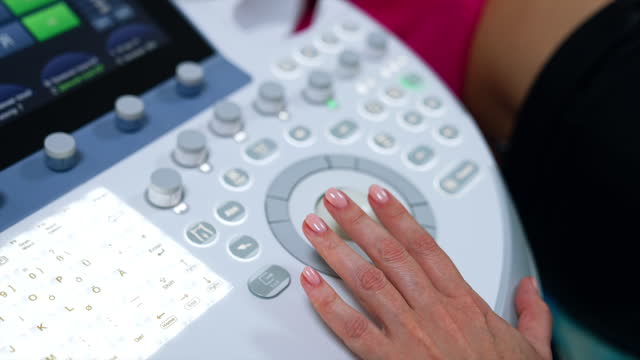 Female medic's hand on the keyboard of ultrasound machine. Doctor is pressing some buttons on the apparatus. Close up.