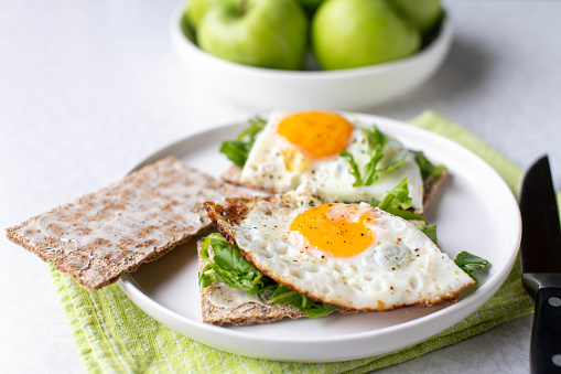 Healthy breakfast plate with a low carb egg crispbread sandwich, arugula and green apples.  Gluten free and vegetarian food