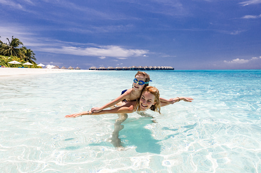 Happy mother and her small boy having fun with their arms outstretched during summer day in sea. Copy space.