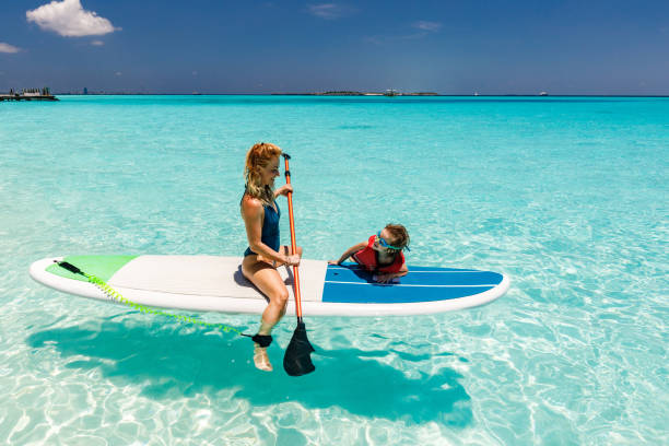 istock Happy single mother and her son talking on a paddleboard in sea. 1535989719