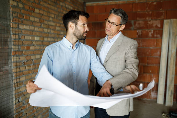istock Male customer and building contractor analyzing blueprints at construction site. 1536005293