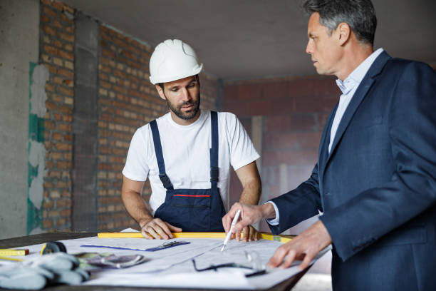 istock Manual worker and foreman going through housing plans at construction site. 1536010526