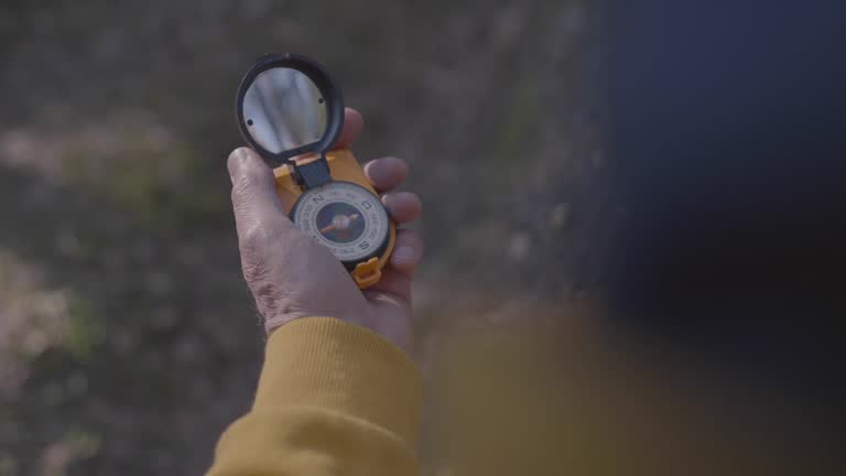 Hiker holding portable compass follows needle in forest