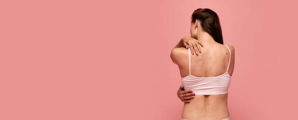 istock Back pains. Rear view image of female body, shoulders, back against pink studio background. Model posing in underwear 1536010678
