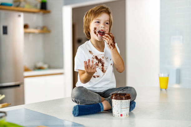 istock Messy little boy eating chocolate from a jar at home. 1536034932