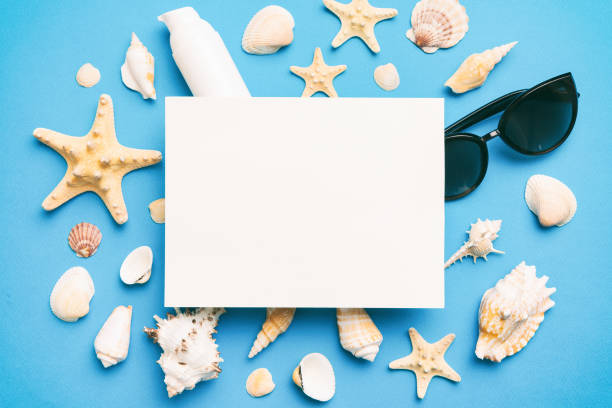 istock Summer time concept with blank greeting card and blank white paper on colored background. Seashells from ocean shore in the shape of frame separated with space for text top view 1536068781