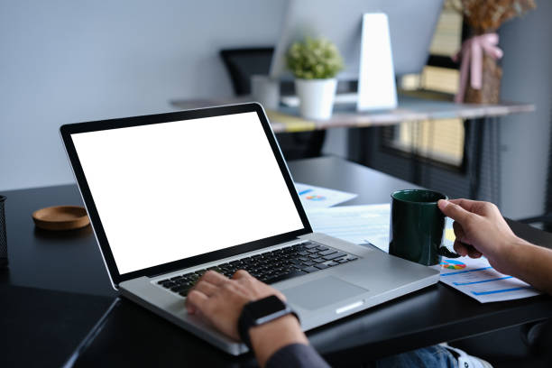 istock Closeup young businessman holding coffee cup and using laptop computer on black office desk. 1536089524