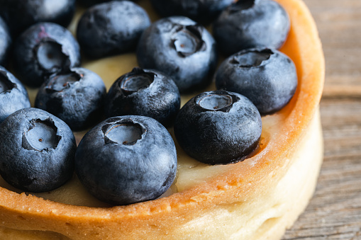 Homemade mini tart with blueberries and whipped cream on a wooden background, close up.