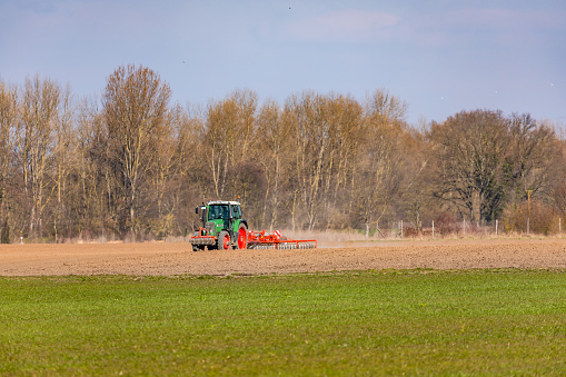 Rural scene with a tractor plowing a field with a plow in winter sunshine