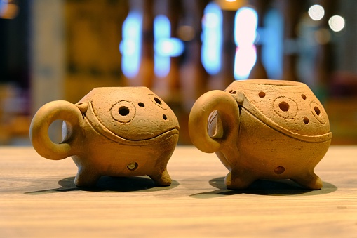 The two clay cups with unique designs placed on a wooden table.