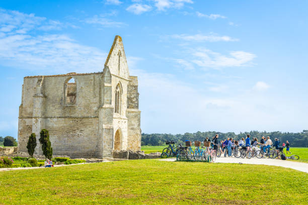Group of tourists on bicycles visiting the ruins of the Abbaye des chateliers in La Flotte Group of tourists on bicycles visiting the ruins of the Abbaye des chateliers in La Flotte, France flotte stock pictures, royalty-free photos & images