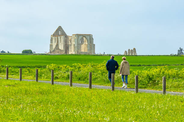 Couple of tourists walking in the countryside near the ruins of the Abbey of Notre-Dame-de-Ré in La Flotte Couple of tourists walking in the countryside near the ruins of the Abbey of Notre-Dame-de-Ré in La Flotte, France flotte stock pictures, royalty-free photos & images
