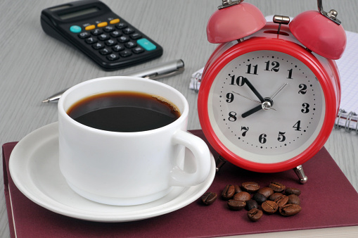 Cup of coffee with coffee beans and an alarm clock