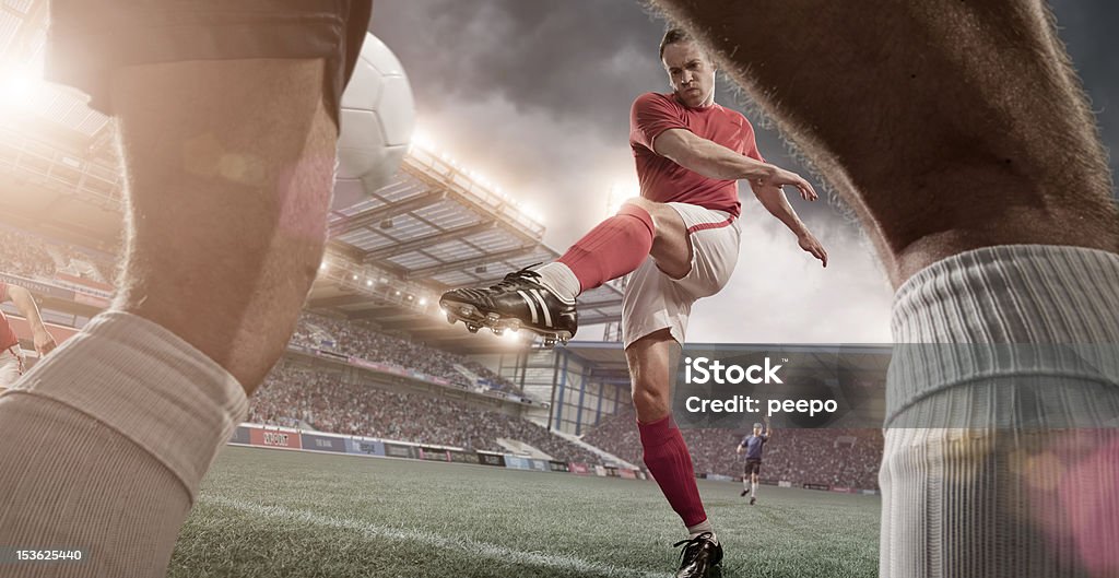 Striker in Mid Game Action Close up view of professional soccer player in floodlit outdoor stadium kicking ball - intentional lens flare Soccer Stock Photo