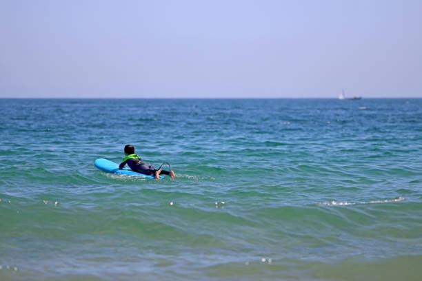 istock A boy surfer lying on his board to catch waves 1536276276