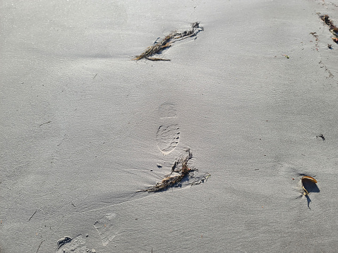 High angle view footprints on the sand at the beach with wave pattern