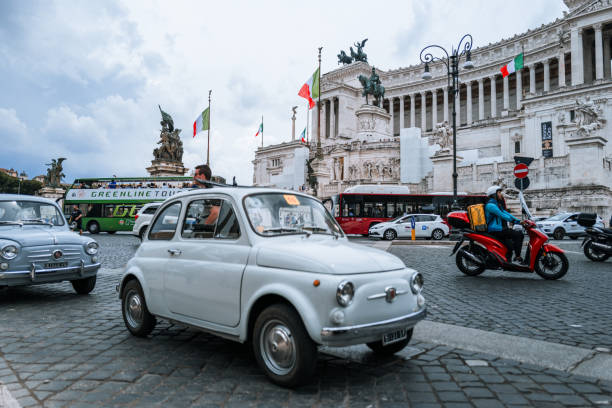 Rome, Italy, June 4, 2023: Vintage car parade on June 4, 2023 in Roma, Italy. Old vintage cars are parked in front of Vittorio Emanuele Monument, participating to a parade. A Fiat 500 attract people attention