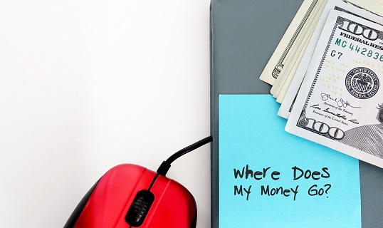 Red mouse, notebook, cash money dollars and blank blue sticky note written WHERE DOES ALL MY MONEY GO?  finding expense leaks,  track spending to boost saving