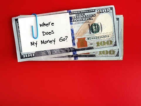 White note clipping with dollar cash money on copy space red background ,written Where Does My Money Go - concpet of money management, finding leaks by tracking spending and fix them to boost saving